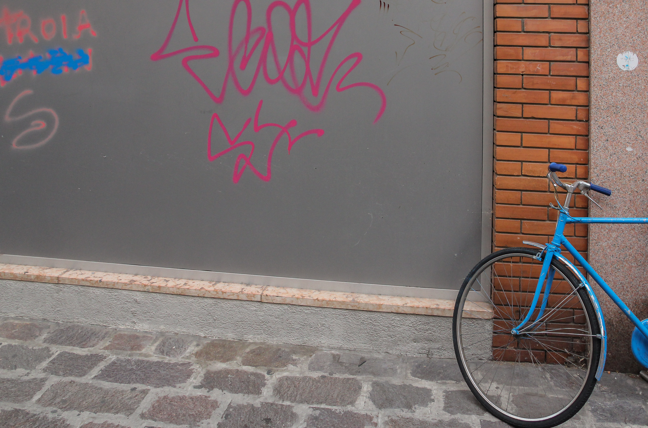 Hellblauer Rahmen an der Ziegelkante, daneben rosa Graffiti